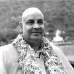 Swami Sivananda wearing garland beside peaceful river