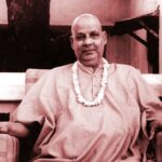 Swami Sivananda seated peacefully wearing flower garland