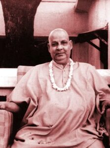 Swami Sivananda seated peacefully wearing flower garland