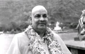 Swami Sivananda wearing garland beside peaceful river