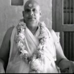 Swami Sivananda wearing flower garland seated peacefully