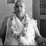 Swami Sivananda wearing flower garland seated peacefully