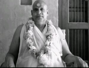 Swami Sivananda wearing flower garland seated peacefully