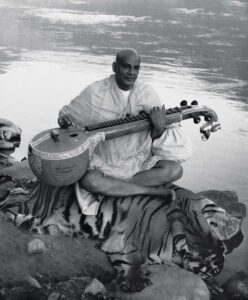 Swami Sivananda playing veena on tiger skin.