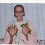 Smiling Swami Chidananda blessing devotees with raised hands and compassion gracefully