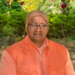 Portrait of Swami Sivananda disciple in saffron robes with peaceful expression outdoors