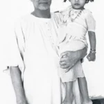 Swami Sivananda holding young child lovingly