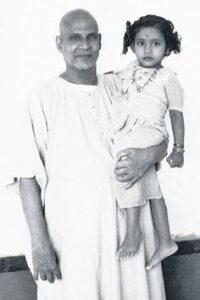 Swami Sivananda holding young child lovingly