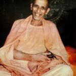 Smiling Hindu monk seated peacefully in saffron robes