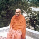 Swami Sivananda seated outdoors beside sacred river