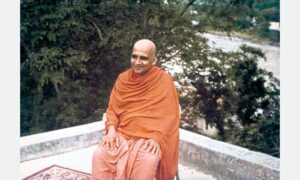 Swami Sivananda seated outdoors beside sacred river