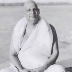 Swami Sivananda sitting peacefully beside sacred river