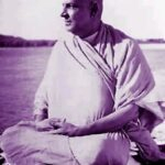 Swami Sivananda meditating peacefully beside sacred river