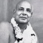 Swami Sivananda wearing sacred flower garland smiling