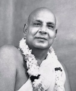 Swami Sivananda wearing sacred flower garland smiling