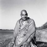 Swami Sivananda wearing ceremonial shawl beside riverside peacefully