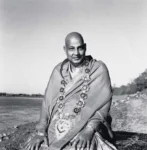 Swami Sivananda wearing ceremonial shawl beside riverside peacefully