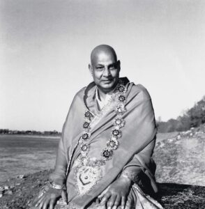 Swami Sivananda wearing ceremonial shawl beside riverside peacefully