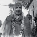 Swami Sivananda wearing flower garland smiling peacefully outdoors