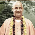 Smiling Swami Sivananda wearing flower garlands outdoors