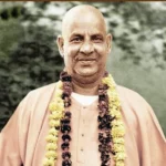 Smiling Swami Sivananda wearing flower garlands outdoors