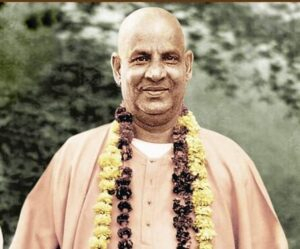Smiling Swami Sivananda wearing flower garlands outdoors