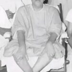 Swami Sivananda seated peacefully among disciples indoors