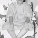 Swami Sivananda seated peacefully among disciples indoors