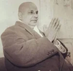 Swami Sivananda sitting with hands in namaste.