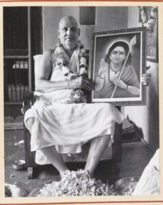 Swami Sivananda holding sacred portrait with reverence