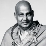 Swami Sivananda smiling with flower garland gracefully