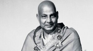 Swami Sivananda smiling with flower garland gracefully