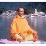 Swami Chidananda meditating peacefully beside sacred Ganga river in Rishikesh India