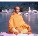 Swami Chidananda meditating peacefully beside sacred Ganga river in Rishikesh India