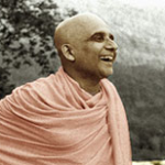 Smiling Hindu monk in saffron robes facing mountain landscape