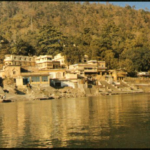 Peaceful riverside spiritual institution surrounded by forested Himalayan landscape