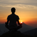 Person meditating peacefully during serene mountain sunset for relaxation