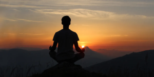 Person meditating peacefully during serene mountain sunset for relaxation