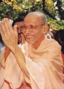 Smiling Hindu monk greeting devotees with folded hands outdoors