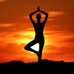 Person practicing yoga meditation at peaceful sunrise silhouette