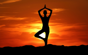 Person practicing yoga meditation at peaceful sunrise silhouette