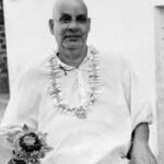 Swami Sivananda seated wearing flower garland with serenity