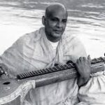 Swami Sivananda playing veena beside the Ganges