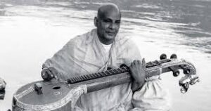 Swami Sivananda playing veena beside the Ganges