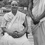 Swami Sivananda seated beside disciple near riverside