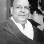 Swami Sivananda smiling in formal coat portrait