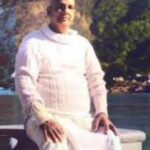 Swami Sivananda seated peacefully beside river inspiring spiritual self-mastery daily