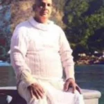 Swami Sivananda seated peacefully beside river inspiring spiritual self-mastery daily
