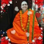 Swami Sivananda seated in orange robes garlanded