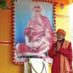 Devotee offering prayers before Swami Sivananda portrait